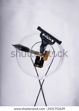 razor, fountain pen, memory card, cufflinks in a transparent glass on a white background
​