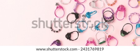 Banner with handmade rings made of wire and natural stones on a pink background. Copy space for text.