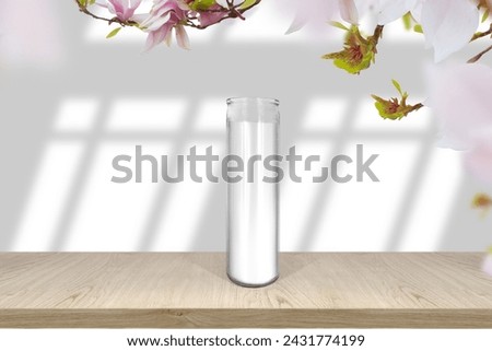 Classic white candle in glass mock up empty shelf with light and window- shadows and magnolia fresh flowers border
