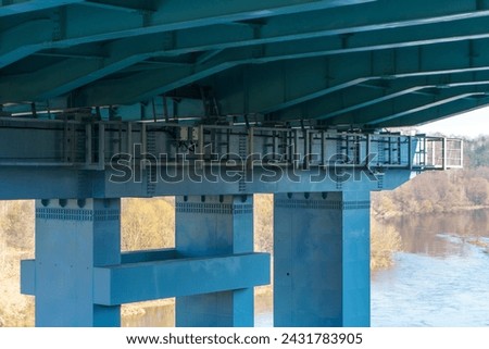 Parts of a modern metal bridge in close-up against a blue sky background. Metal structures connected by large bolts and nuts to a reinforced concrete base. Railway or automobile bridge. Royalty-Free Stock Photo #2431783905