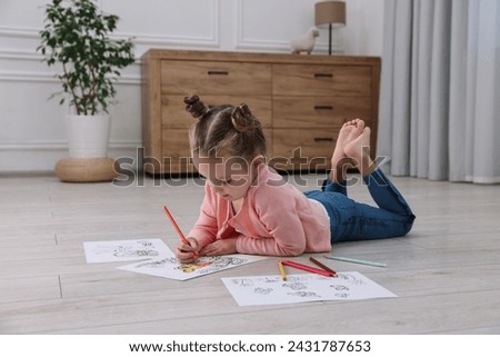 Cute little girl coloring on warm floor at home. Heating system