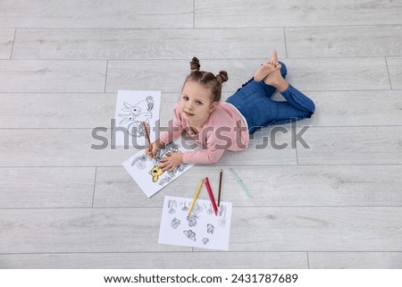 Cute little girl coloring on warm floor indoors. Heating system