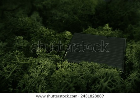 Close-up of a solar panel laying on a bed of vibrant green moss, highlighting renewable energy and eco-friendly technology Royalty-Free Stock Photo #2431828889