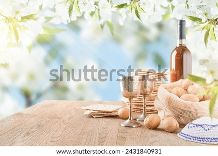 Passover celebration concept. Matzah, red kosher and walnut on wooden vintage table table in front of spring blossom tree garden and flowers landscape with sun rays with copy space. Mock up.