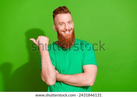 Photo of cheerful cool guy wear t-shirt showing thumb empty space isolated green color background