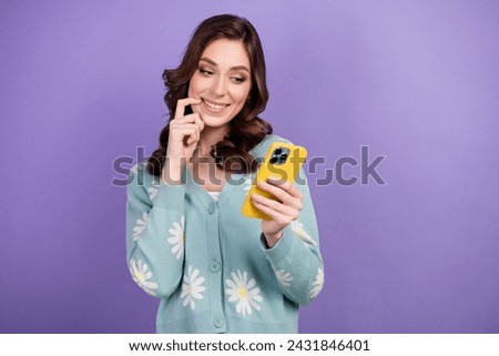 Photo of wavy brunette hair woman creating wish list in smartphone choosing which things she want isolated on purple color background