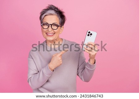 Photo of cheerful funny retired woman showing gadget recommend buy credit modern device isolated on pink color background