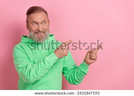 Photo of funky dreamy man wear green sweatshirt looking pointing two fingers empty space isolated pink color background