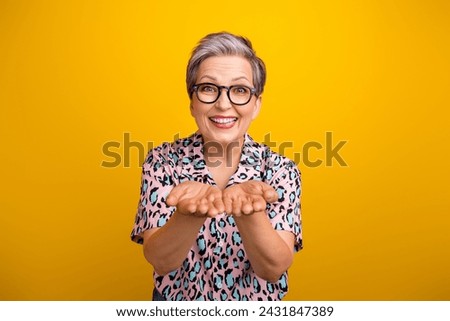 Photo portrait of lovely senior lady hold excited empty space dressed stylish leopard print garment isolated on yellow color background