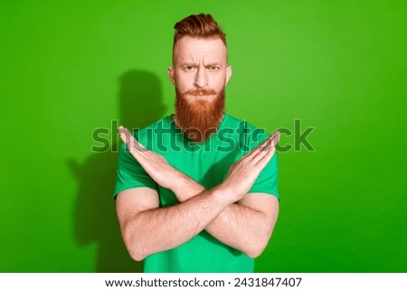 Photo of serious strict man with ginger beard dressed stylish t-shirt showing stop hands crossed isolated on green color background