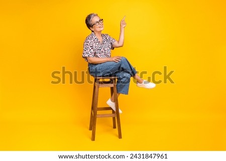 Full size photo of pretty retired female chair point look empty space wear trendy leopard print outfit isolated on yellow color background
