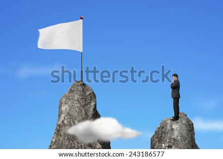 Businessman standing on peak with blank white flag and natural sky cloud background