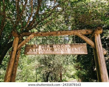 Entrance sign of Muir Woods National Monument surrounded by lush greenery.