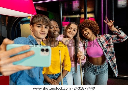 Selfie of multiracial friends in arcade room playing billiard