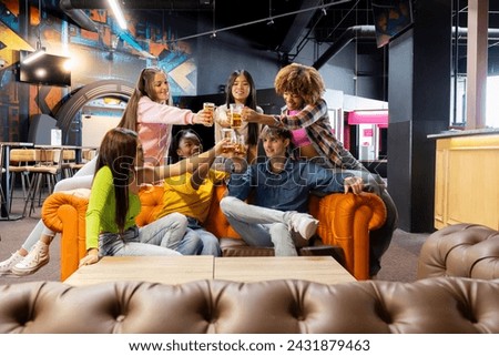 group of young multiracial friends toasting with their glasses of beer in a recreational place celebrating their meeting on the weekend Royalty-Free Stock Photo #2431879463