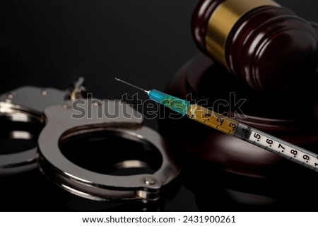 Syringe with gavel and handcuffs. Lethal injection, death penalty and capital punishment concept. Royalty-Free Stock Photo #2431900261