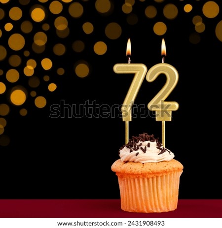 Birthday candle with cupcake - Number 72 on black background with out of focus lights Royalty-Free Stock Photo #2431908493
