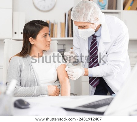 Doctor giving Covid-19 or flu antivirus vaccine shot to patient wear face mask protection at medical office Royalty-Free Stock Photo #2431912407