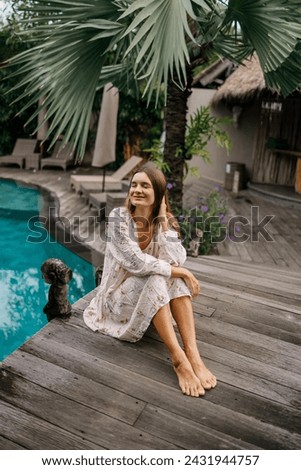 Beautiful caucasian lady in dressi sitting near swimming pool   at tropical summer resort, closed eyes, meditation Royalty-Free Stock Photo #2431944757