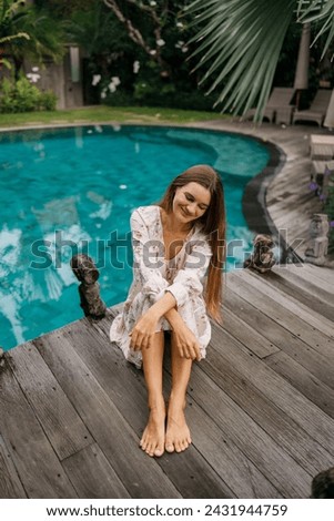 Beautiful caucasian lady in dressi sitting near swimming pool   at tropical summer resort, closed eyes, meditation Royalty-Free Stock Photo #2431944759