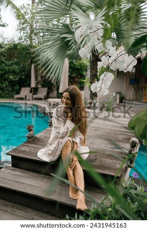 Beautiful caucasian lady in dressi sitting near swimming pool   at tropical summer resort, closed eyes, meditation Royalty-Free Stock Photo #2431945163