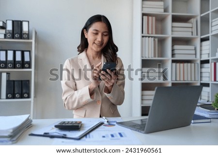 Smiling beautiful young Asian businesswoman ready to press the phone Talking on the mobile phone in the office with a happy smile.