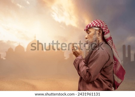 A Muslim man with agal raised her hands and prayed to Allah with a dramatic sky background. Muslim concept Royalty-Free Stock Photo #2431961131