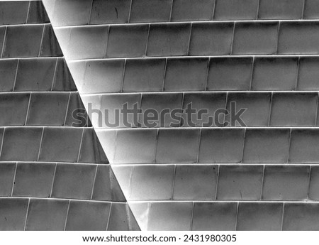 Dive into the world of architectural elegance with this striking black and white stock photo, featuring the intricate geometric patterns of a modern building's tiled facade.