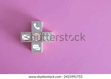 Contact us icons on wooden blocks on wooden desk. Copy space. Color background.