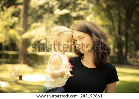 Adorable toddler girl touching her Mom in the park. Eyes closed. Summer Colorful natural light