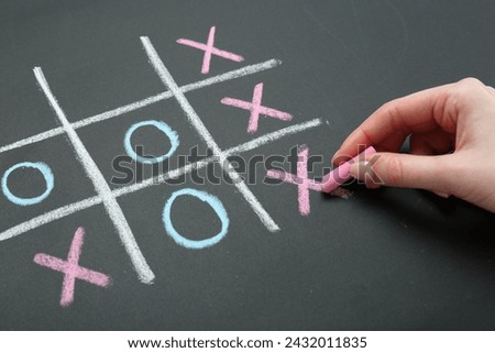 Woman playing tic tac toe on chalkboard, closeup