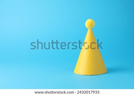 Yellow party hat on light blue background, space for text