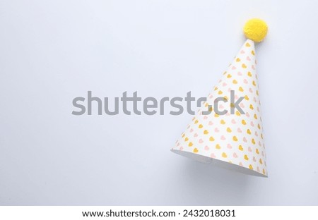 One party hat with hearts on light background, top view. Space for text