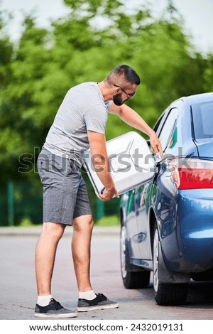 Forced stop because of ran out of fuel. Skilled driver refueling car gas tank with gasoline from canister he picked for unforeseen circumstances. Royalty-Free Stock Photo #2432019131