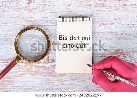 Bis dat qui cito dat It is translated from Latin as The one who gives twice is the one who gives quickly written in pencil on a notebook