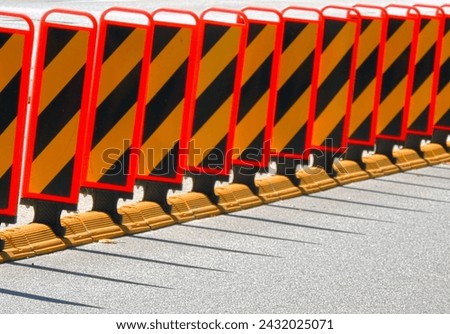 This high-resolution stock photo highlights the striking visual pattern of diagonal stripes on bright orange street barriers, a common sight in areas of construction or temporary obstruction.
