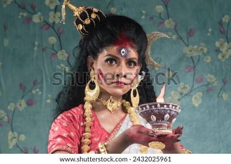 Portrait of beautiful Indian girl of Durga idol Agomoni Concept Indoor Photo. wearing traditional Indian saree, gold jewellery,Maa Durga agomoni shoot concept .Indian culture durga puja.