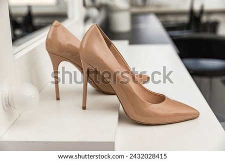 Women's high-heeled shoes of beige color stand on a white table for makeup