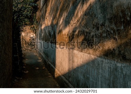 Narrow alley with textured walls lit by warm sunlight, creating a moody atmosphere.