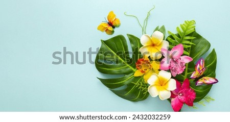 Summer background with tropical orchid flowers,butterflies and green tropical palm leaves on light background. Flat lay, top view.