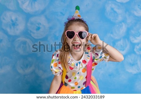 Funny kid clown playing against a bright wall. 1 April Fool's day concept, birthday concept.