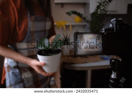 A young woman films a video blog and happily plants bright flowers. Reflecting the essence of gardening and flower care, the art of growing plants. Suitable for lifestyle, gardening and vlogging.