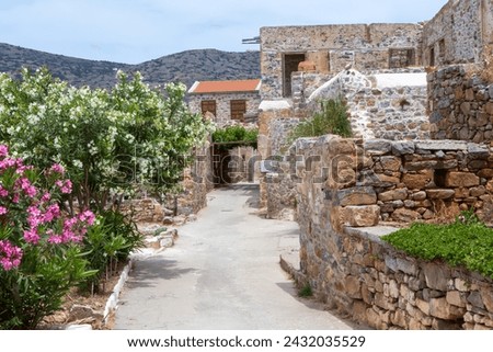 Ruined houses and flower lined street on the former leper colony on the island of Spinalonga, Crete, Greece. Royalty-Free Stock Photo #2432035529