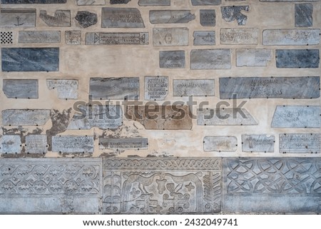 Marble tiles with pagan and early Christian Latin inscriptions on a wall in the portico of the Basilica of Santa Maria in Trastevere in Rome, Italy