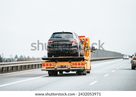 Emergency roadside assistance in action as a tow truck carries a broken down SUV on the highway. Royalty-Free Stock Photo #2432053971