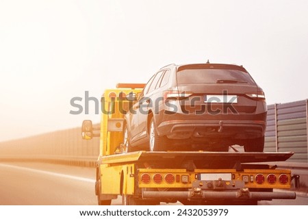 A tow truck with a flatbed is ready to assist you in case of a vehicle breakdown or accident on the highway and urban city streets. Car accident and towing assistance insurance. Royalty-Free Stock Photo #2432053979