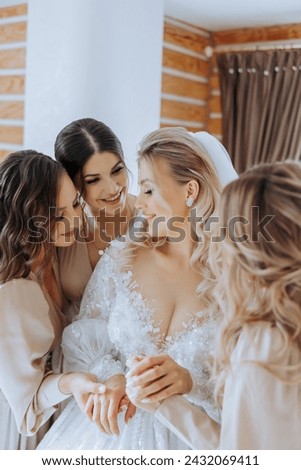 Bridesmaids rejoice in the morning, helping to fasten the buttons on the wedding dress and prepare for the wedding ceremony. They take pictures, smile, help the bride with her shoes.