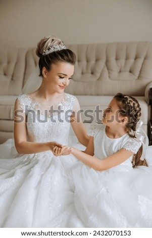 Portrait of the bride with her little sister in the room. Tender and sweet photo of a beautiful bride with her little sister.