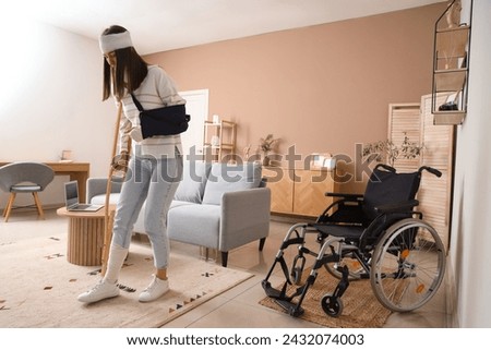 Injured young woman after accident with crutch walking at home Royalty-Free Stock Photo #2432074003