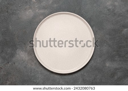 Empty beige plate on a dark grunge background. Top view, flat lay, copy space. Royalty-Free Stock Photo #2432080763